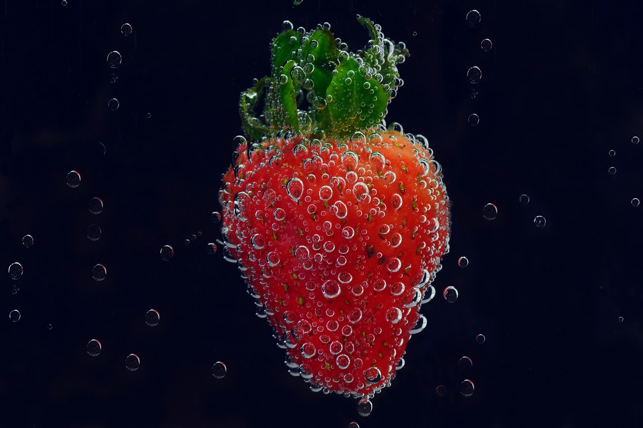 Erdbeere mit Luftblasen im dunklem Wasser