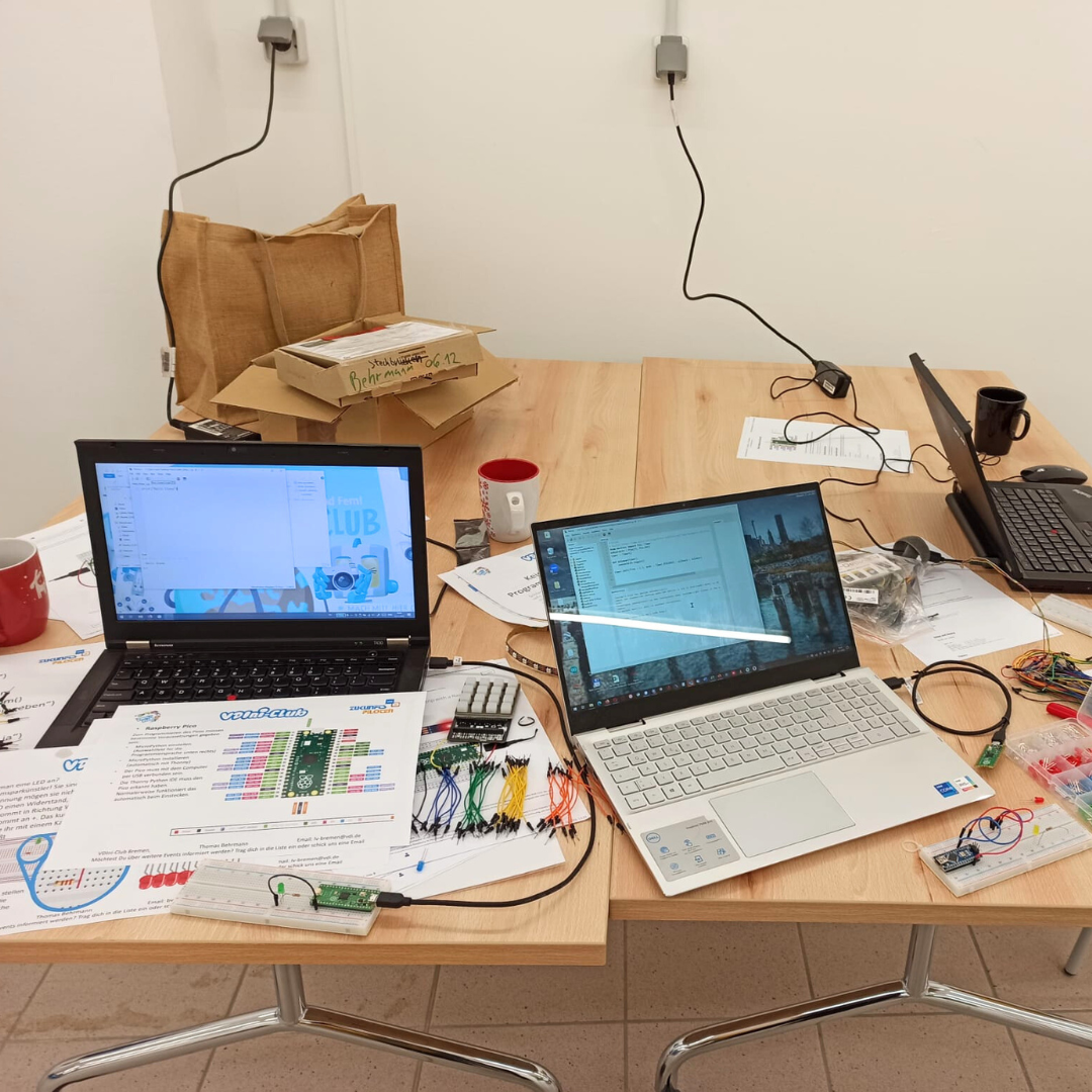Tisch mit Laptops und Material zum Programmieren