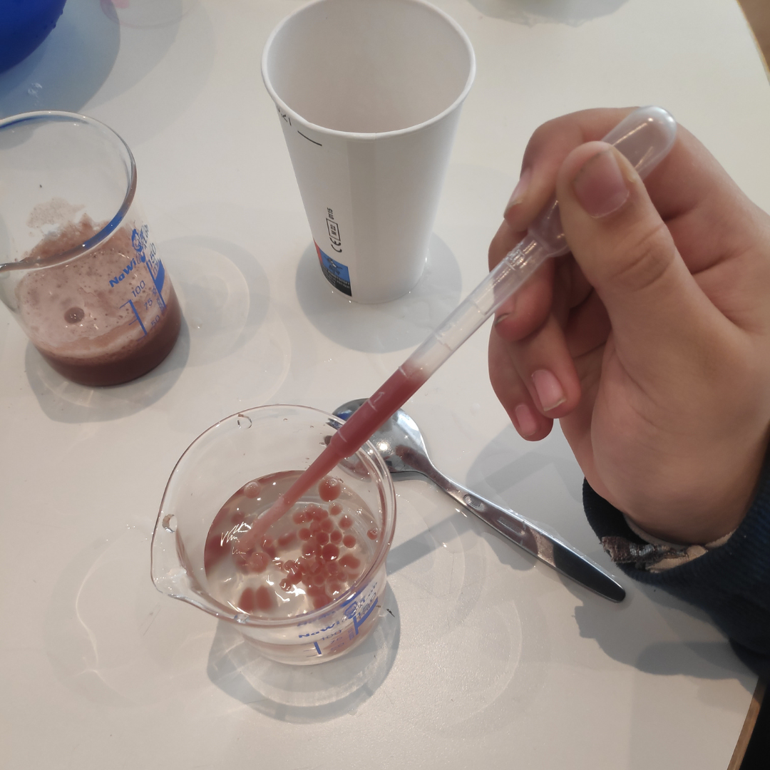 Bunte Blasen werden mit einer Pipette in ein Reagenzglas getropft 